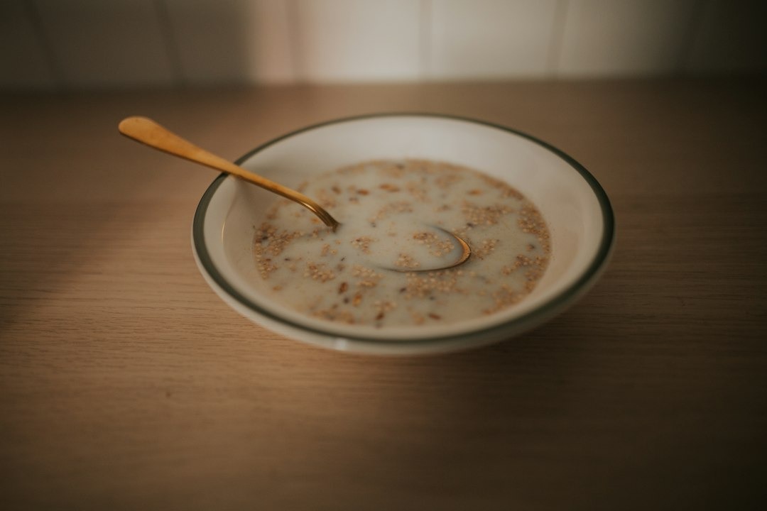 A golden spoon rests inside a bowl of milk and grains.